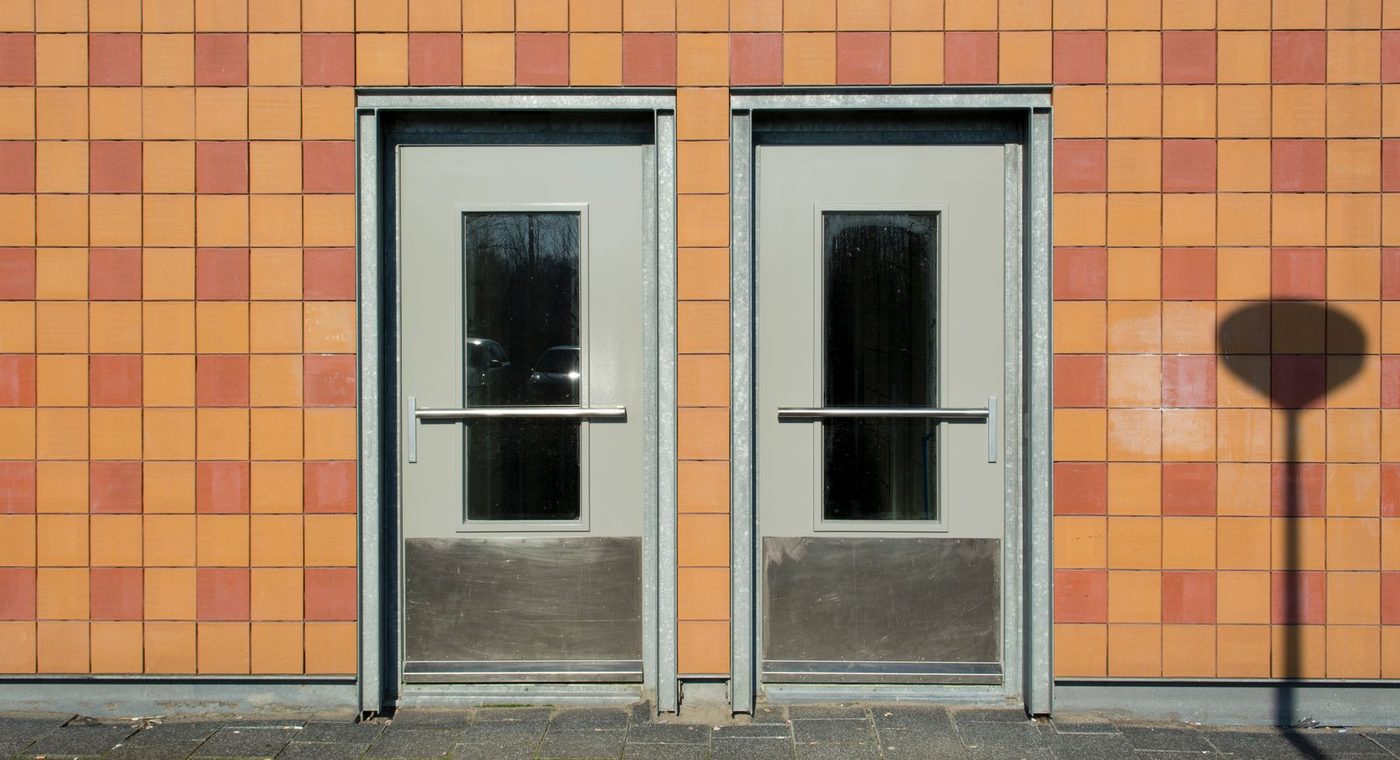 A glass storefront door with a mag lock and a request-to-exit button on the inside